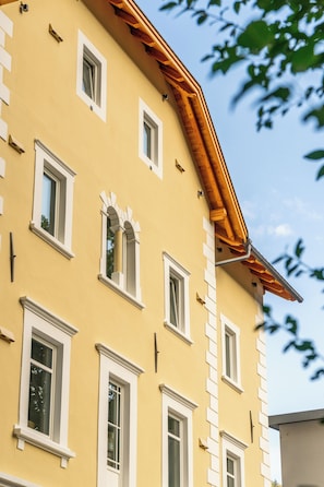 A yellow building with multiple windows and a wooden roof structure. - Aparthotel Krone 1895 (Klausen)