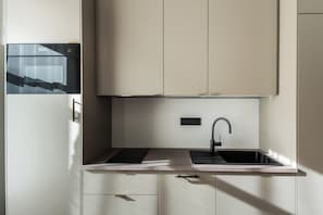 A modern kitchen with a built-in oven, a sink, and a countertop. - Aparthotel Krone 1895 (Klausen)