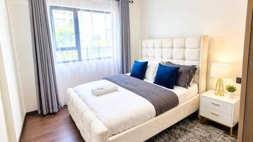 A modern bedroom with a bed, bedside tables, and a view of the outdoors.