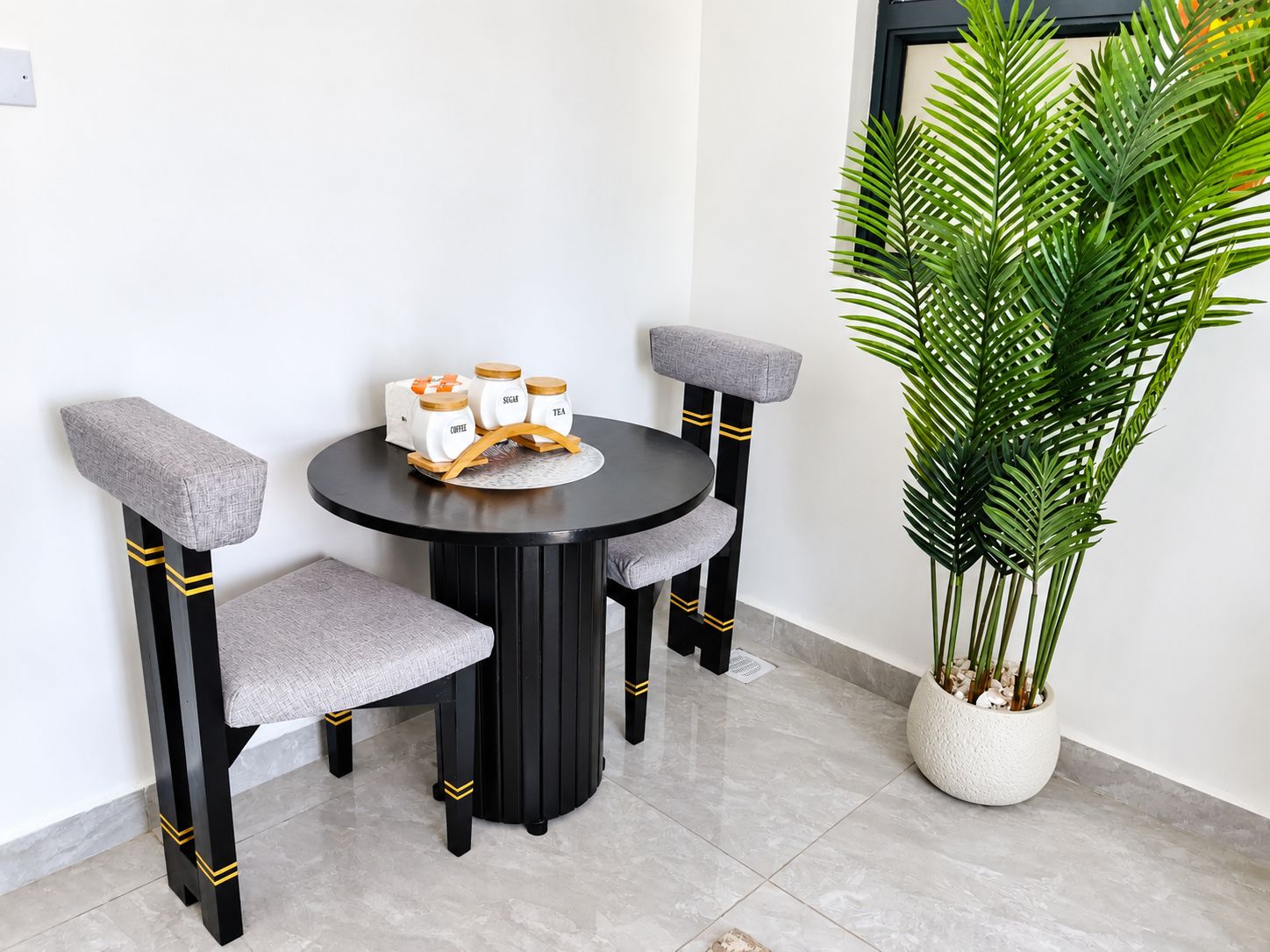 A round table with a black and gold chair design, accompanied by a potted plant.
