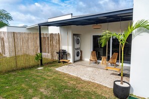 Eine moderne Außenpatio mit überdachter Sitzgruppe, einer Waschmaschine und einem Grill.