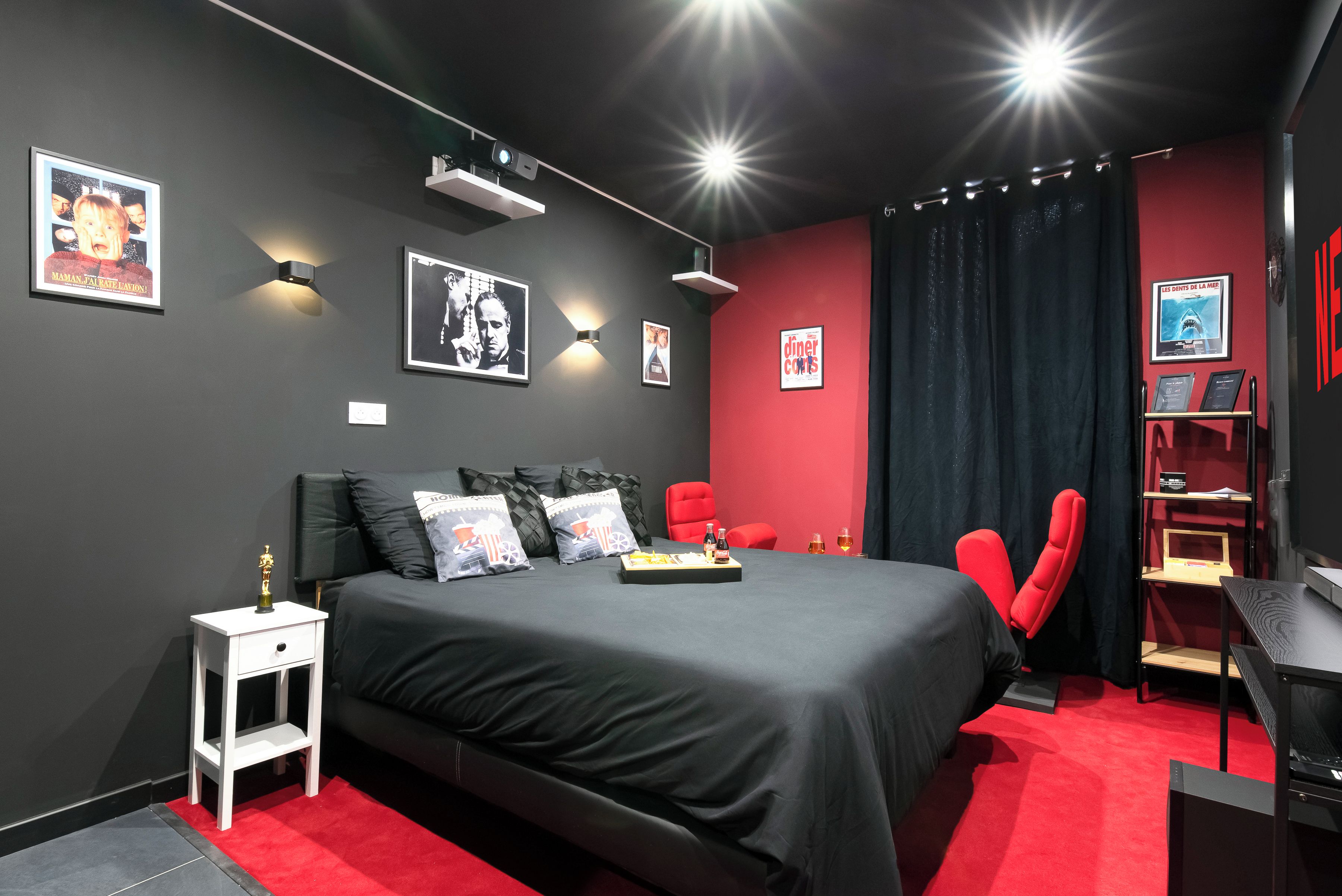 A modern bedroom with a black bed, red accents, and wall-mounted artwork.