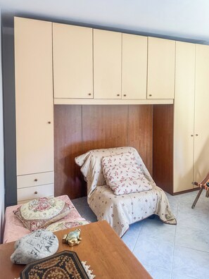 Ein Schlafzimmer mit einem Bett, einem Nachttisch aus Holz, einem Zierkissen und einem Kleiderschrank.