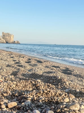 Ein Kiesstrand mit einer Burg im Hintergrund.