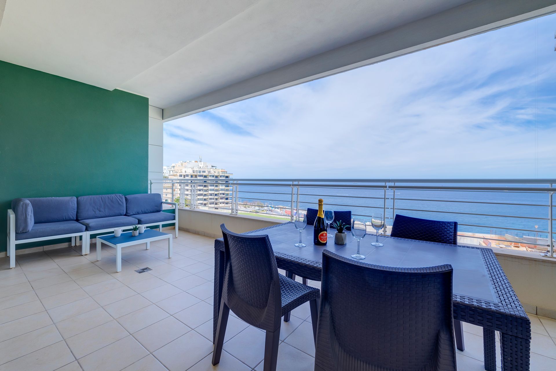 Un balcon avec une table à manger, des chaises et un canapé.