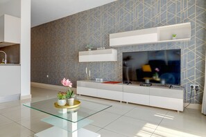 A modern living room with a flat-screen TV, white cabinetry, and a patterned wall. - Luxury Apartment With Balcony, Central Area (Gzira)