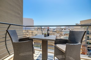 Ein Balkon mit Korbstühlen und einem Tisch mit Blick auf die Stadtlandschaft.