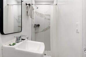 A bathroom with a white sink, a mirror, a shower with a glass door, and a towel rack. - Cozy Smoking Queen Bed Retreat in Vibrant Inglewood (Inglewood)