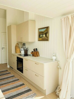 A kitchen with a built-in oven, a coffee maker, and a knife block on the counter. - Newly built dream summer house on Sjællands Odde (Sjællands Odde)