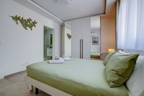 Ein Schlafzimmer mit einem Bett, einem Spiegel, einer Badezimmertür und einem Fenster mit Vorhängen.