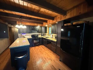 A kitchen with wooden cabinets, a black refrigerator, and a granite countertop. - Spacious 3-Bedroom Retreat in the Poconos - WLE Amenities (Lake Ariel)