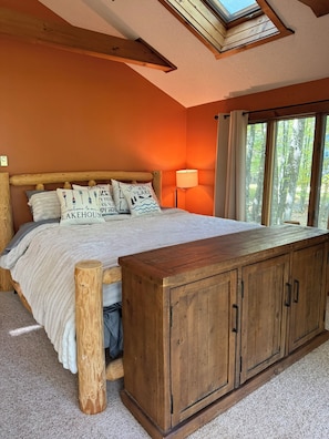 A bedroom with a wooden bed, a nightstand, a lamp, and a large window with curtains. - Spacious 3-Bedroom Retreat in the Poconos - WLE Amenities (Lake Ariel)