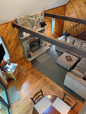 A cozy cabin interior with a stone fireplace, wooden floors, a sofa, and a dining area. - Spacious 3-Bedroom Retreat in the Poconos - WLE Amenities (Lake Ariel)