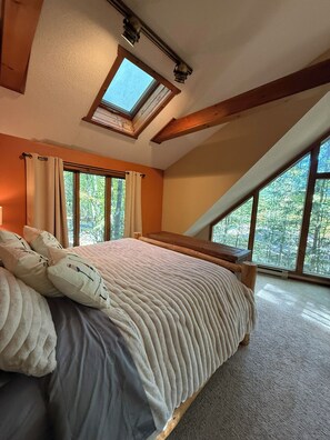 A bedroom with a large bed, two windows, a skylight, and wooden beams. - Spacious 3-Bedroom Retreat in the Poconos - WLE Amenities (Lake Ariel)