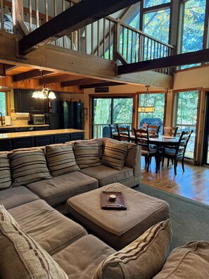 A spacious living area with a large sectional sofa, a dining table with chairs, and a kitchen in the background. - Spacious 3-Bedroom Retreat in the Poconos - WLE Amenities (Lake Ariel)