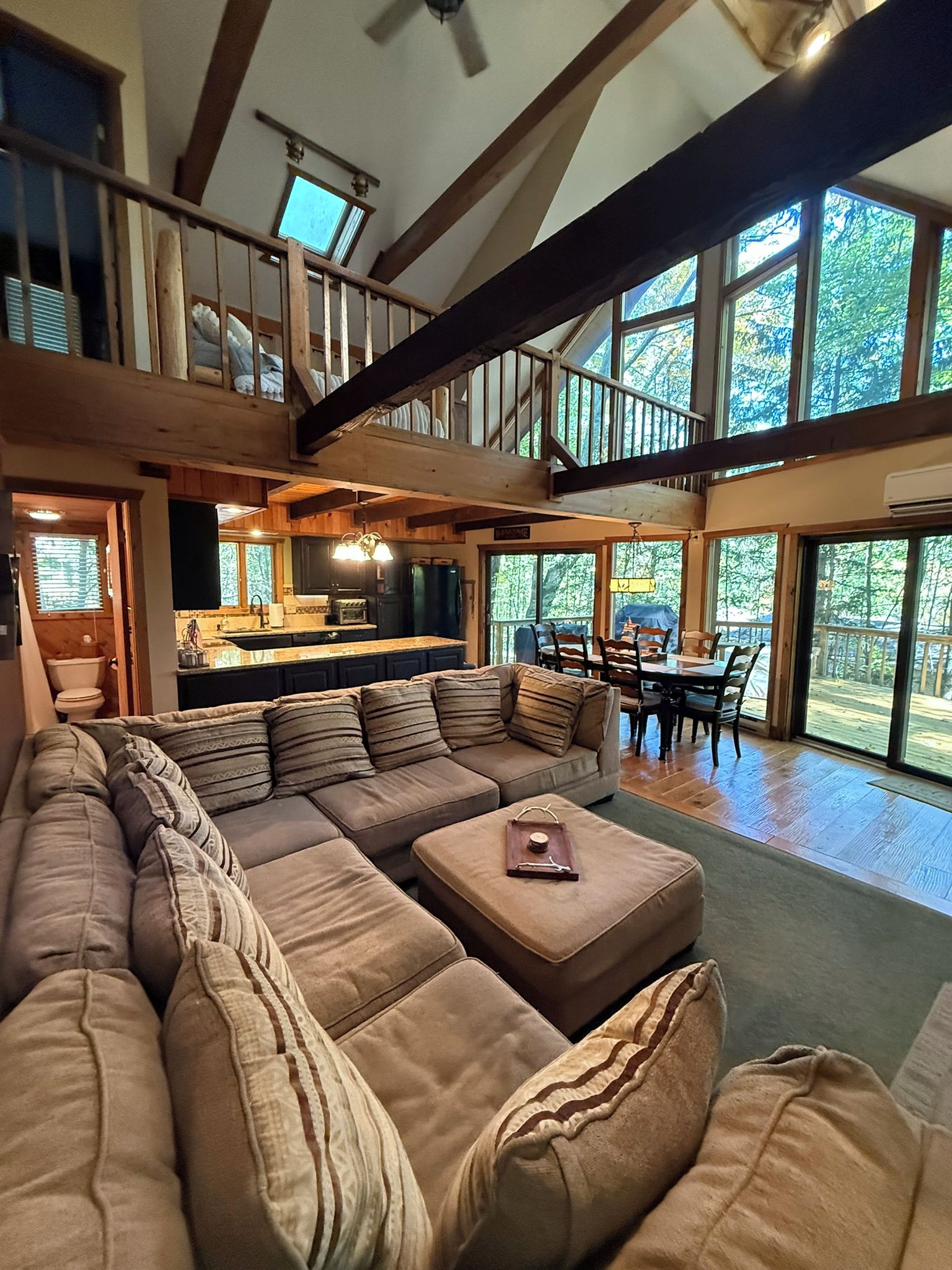A spacious living area with a large sectional sofa, a dining table with chairs, and a kitchen in the background.