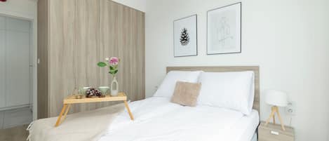 A modern bedroom with a bed, bedside table, and artwork on the wall.