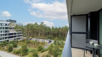 Ein Balkon mit Tisch und Stühlen, mit Blick auf einen Parkplatz und ein mehrgeschossiges Gebäude.
