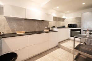 Eine moderne Küche mit weißen Schränken, einer schwarzen Arbeitsplatte und einem Edelstahl-Kühlschrank.