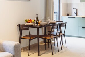 A dining area with a table set for four, chairs, a bowl of fruit, wine glasses, and a bottle of wine. - Modern Sliema Stay in the Heart of Sliema (Sliema)