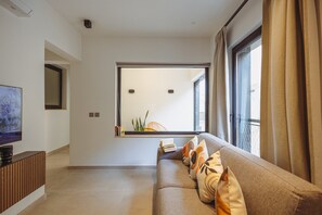 A modern living room with a sofa, a television, and a large window with curtains. - Modern Sliema Stay in the Heart of Sliema (Sliema)