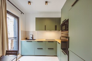 A modern kitchen with a built-in oven, a sink, and a window with curtains. - Modern Sliema Stay in the Heart of Sliema (Sliema)