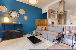 A modern living room with a blue accent wall, a sofa, a coffee table, and a TV stand. - Spacious 3-bedroom Apartment in Central G ira (Gzira)