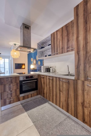 Une cuisine moderne avec des meubles en bois, un four encastré et un pare-feu en marbre.