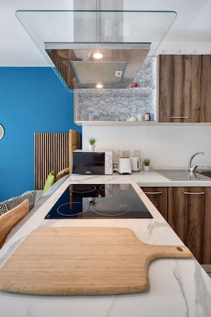 Eine moderne Küche mit Einbauherd, Schneidebrett aus Holz und Marmorfliesenspiegel.