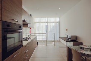 A modern kitchen with a gas stove, oven, and microwave. There is a dining area with a table and chairs.