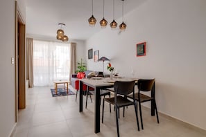 A dining area with a table set for four, a sofa, and a floor lamp. - Charming Central Apartment, Your Perfect Getaway (Msida)