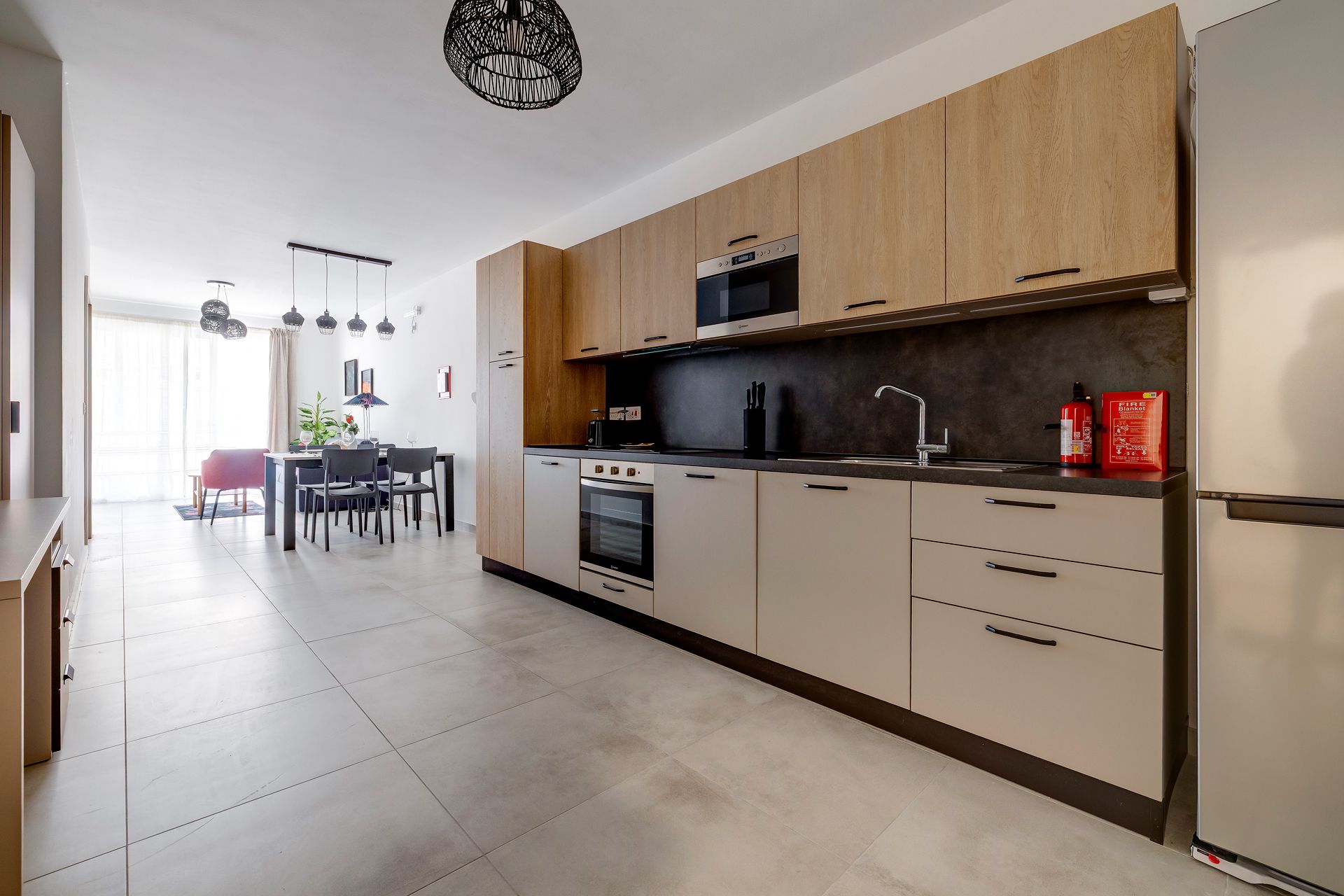 A modern kitchen with wooden cabinets, a built-in oven, and a stainless steel refrigerator.