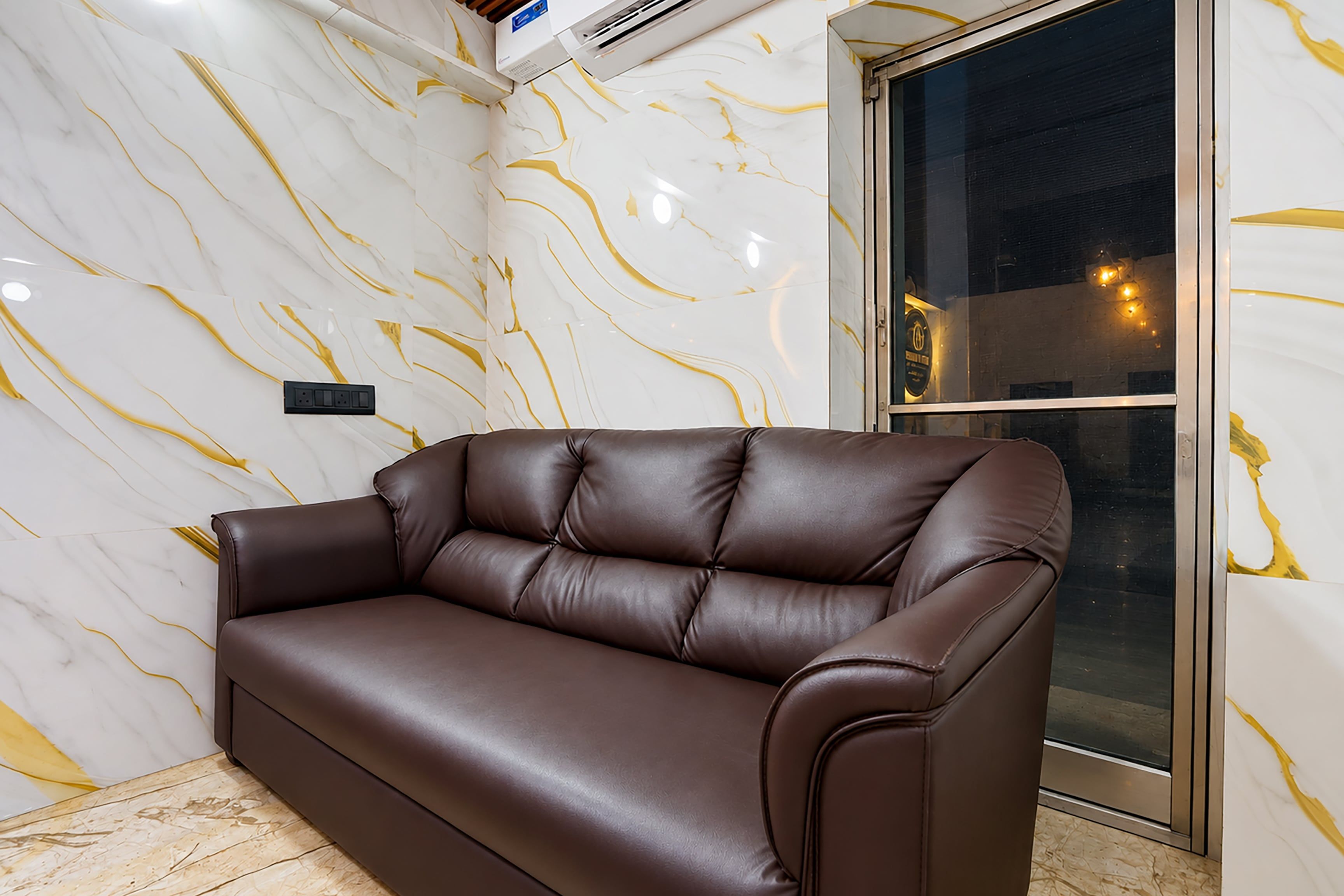 A brown leather sofa against a wall with a marble pattern.