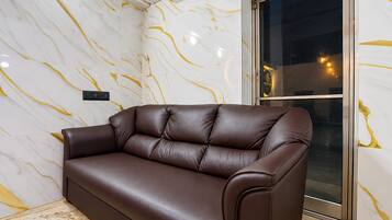A brown leather sofa against a wall with a marble pattern.