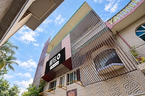 Un hotel con un cartel llamativo, un balcón con barandillas de metal y una fachada con diseño.