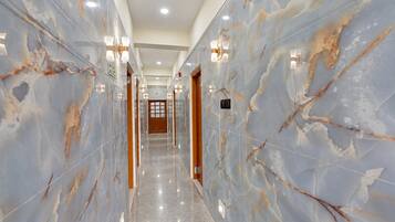 Un pasillo con paredes de mármol, iluminación empotrada y piso pulido.
