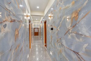 A corridor with marble walls, recessed lighting, and a polished floor. - Hotel O Puri Railway Station (Puri)
