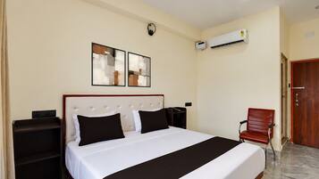 Een hotelkamer met een bed, nachtkastjes, een stoel, een airconditioning en een deur.