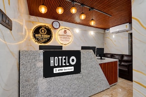 Una mesa de recepción de hotel con un cartel que indica que ofrece servicios OYO. Hay dos placas sobre la mesa, una para Hotel Harmony y otra para Dhanashree Homestay, ambos ubicados en Puri, Odisha.