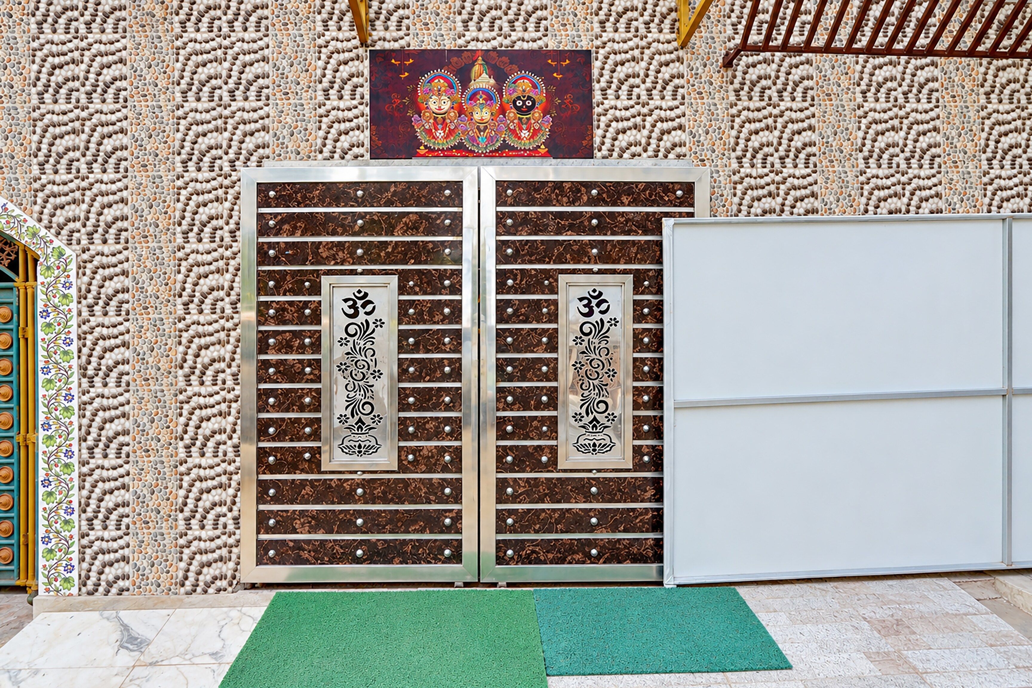 Habitació amb una porta decorativa que presenta símbols religiosos, un estri sobre la tarima i una paret amb un disseny.