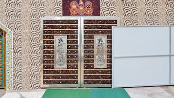 Habitació amb una porta decorativa que presenta símbols religiosos, un estri sobre la tarima i una paret amb un disseny.