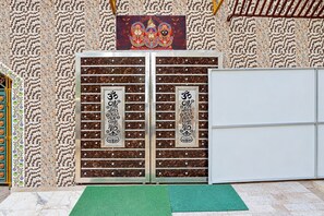 A room with a decorative door featuring religious symbols, a green mat on the floor, and a patterned wall. - Hotel O Puri Railway Station (Puri)