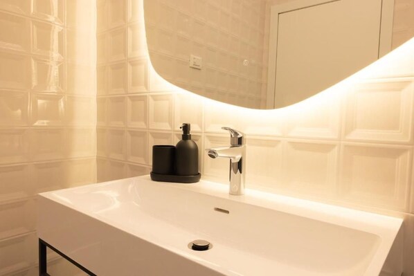 A bathroom with a white sink, a mirror, and a faucet. - LOFT ZAI (Verona)
