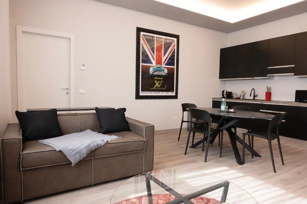 A modern living room with a sofa, a glass coffee table, and a dining area with a table and chairs.