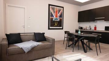 A modern living room with a sofa, a glass coffee table, and a dining area with a table and chairs.