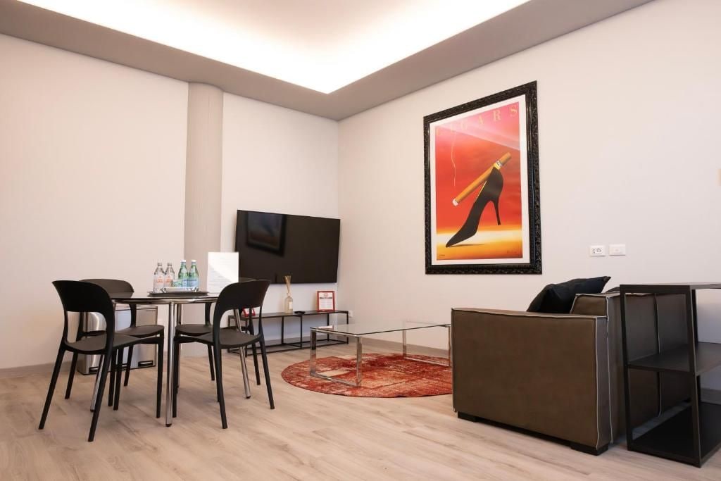 Habitació moderna amb zona de menjador, un sofà, televisió i una obra d'art emmarcada.