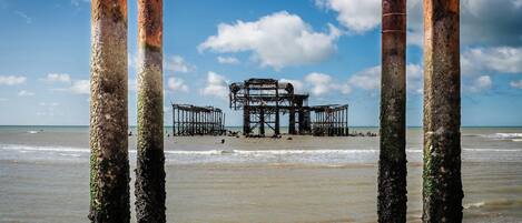 A beach with a structure in the background, viewed through rusted poles.