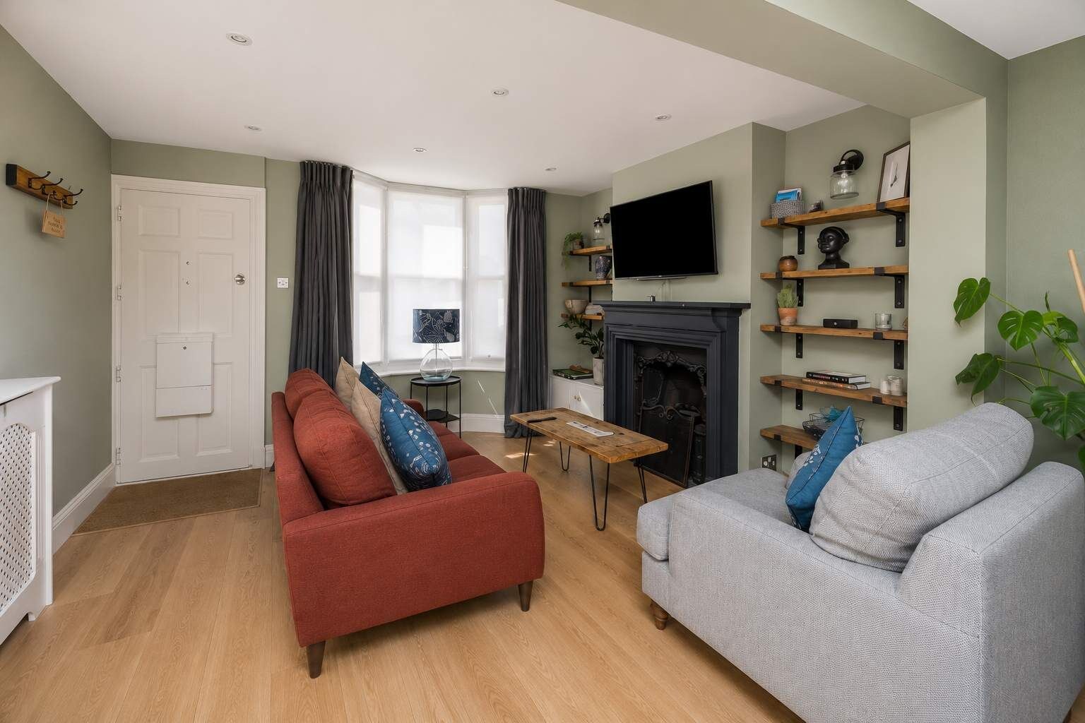 A living room with a fireplace, a television mounted above it, and a sofa with cushions.