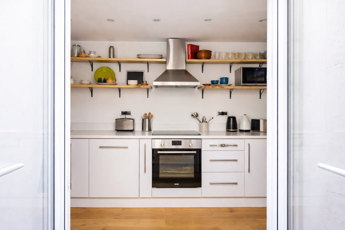 A practical, modern kitchen showcasing the full oven, generous storage, and clear access to the patio. Bright and uncluttered, the layout makes cooking easy while connecting seamlessly to the outdoor space for relaxed, everyday living.