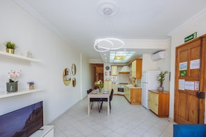 A modern kitchen with a dining area, wooden cabinets, and a fire exit sign. - Spacious 2BR Sliema Apartment (Sliema)